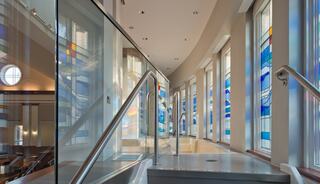 Baptismal font features elegant glass railings and colorful stained glass windows..