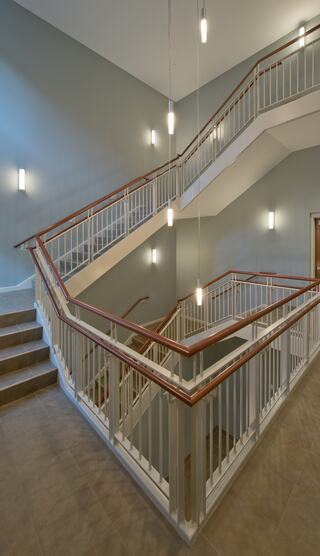 A well-lit staircase with a curved design, featuring wooden railings and soft blue walls, enhancing a contemporary aesthetic.