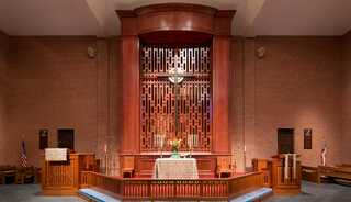 A serene church interior featuring a wooden reredos.