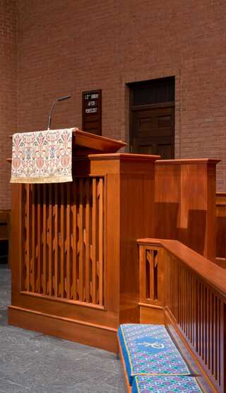A wooden reredos set against a brick wall, reflects a serene atmosphere in a place of worship.