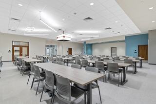 A spacious modern classroom features long tables and chairs, with neutral tones and bright lighting creating an inviting learning environment.