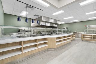 Modern kitchen space featuring sleek cabinetry, glass partitions, and stainless steel appliances under soft lighting. Neutral tones create a welcoming vibe.