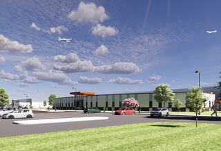 A modern building with a landscaped area, parked cars, and trees, set against a blue sky with clouds and planes flying overhead.