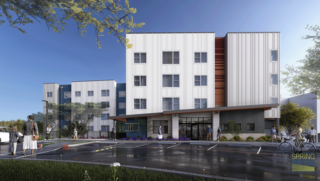 A modern multi-story building features sleek design elements, large windows, and a welcoming entrance, set in a landscaped area with people nearby.