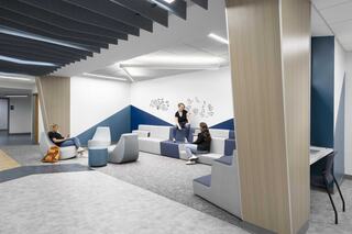 A modern lounge area with comfortable seating, wooden accents, and people engaging in conversation, creating a relaxing atmosphere.