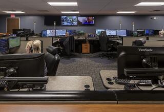 A control room with multiple workstations, monitors displaying data, and staff engaging in their tasks, focused on operations.