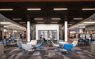 A modern library interior with sleek furniture, organized bookshelves, and a quiet reading area, promoting a calm atmosphere.