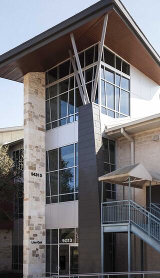 A children's ministry building features large glass windows, a stone facade, and a distinctive angled roof, showcasing a sleek architectural design.