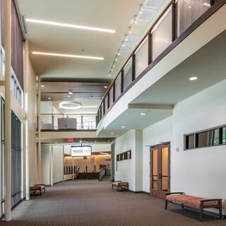 A spacious, modern church interior featuring large windows, sleek lighting, and a two-level design, creating an open and inviting atmosphere.