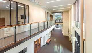 A spacious, modern church interior with a second-floor balcony overlooking a well-lit common area and large windows.