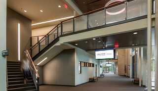 A baptist church interior featuring a spacious, well-lit hallway with stairs, welcoming signage, and a blending of wood and soft color tones.