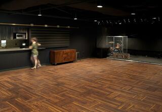 Moody and modern Students Assembly and Kitchenette at The Austin Stone West church's campus, featuring bold new wood flooring, a stage, overhead lighting and a modern look.