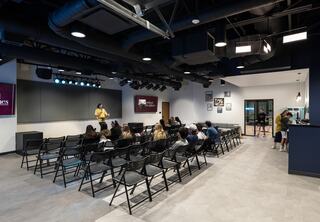 Students Assembly at The Austin Stone South church with comfortable chairs, minimal stage lighting, television screens on each side and a kitchenette in the back.