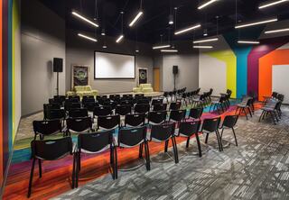 Youth assembly at Cityview Church featuring bold, colorful striped carpet sections that run across the floor, meeting and matching with bold colorful paint stripes that continue upward.