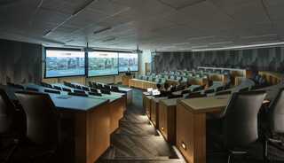 A modern, spacious conference room with curved seating, large screens, and a professional atmosphere, ideal for presentations and meetings.