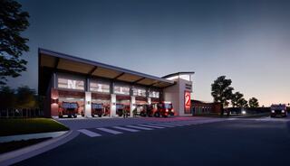 A modern fire station architectural rendering at dusk features large bays for fire trucks, illuminated signage, and a sleek design amidst a landscaped area.