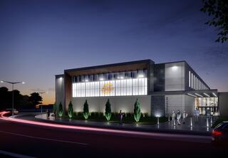 A modern school rendering features large windows and sleek design, illuminated at dusk with greenery and people gathered outside.