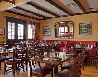 A cozy restaurant interior featuring wooden beams, red booths, and neatly set tables, creating an inviting dining atmosphere.