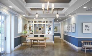 A welcoming space featuring blue walls, decorative displays, framed artworks, a wooden table, and stylish lighting fixtures.