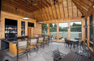 A cozy wooden bar area with a stylish counter, ample seating, and large windows overlooking a serene outdoor space.