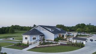 A modern building surrounded by well-maintained landscaping, with green lawns and trees in the background, creating a serene atmosphere.