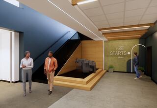 A modern indoor space at the new St. Louis Community College Transportation Education Center featuring a staircase, sleek design, and motivational wall art inviting progress, with three people walking casually.