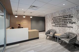A modern reception area with warm lighting, featuring a desk, comfortable seating, and an inspirational wall graphic about dispatchers.