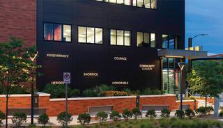 A fire station features inspirational words like "Perseverance," "Courage," and "Community Leaders" on its exterior, surrounded by greenery.