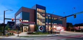 New Arlington Fire Department Station 8 photographed at dusk with the interior lights glowing inside and a hire engine pulling out of the center bay with lights blazing.