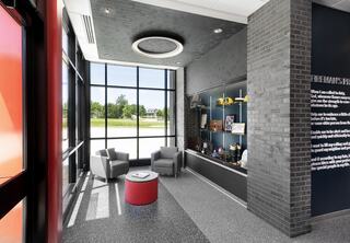 New Godfrey Fire Protection District's Station No. 1 entry lobby, featuring the district's heritage and a memorial wall on one side and the fireman's prayer on the next wall leading into a hallway. Expansive windows let natural light flood the lobby.