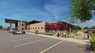 A modern building featuring a contemporary design, landscaped areas, and parking spaces, suggesting a public facility like a police station.