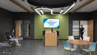 A modern educational space featuring a welcome screen, communal tables, comfortable seating, and a welcoming atmosphere for learners.