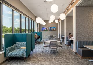 Shared amenity break space with private single seating options, round dining tables and booth seating offers flexiblity. Large perimeter windows face the private staff patio and green vegetative roof.