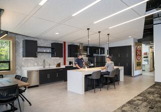 Two fire personnel are in a modern kitchen with a large eat-in countertop island and a dining table to the side.