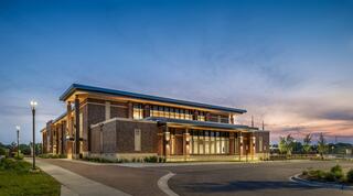 Exterior of new Downers Grove Civic Center photographed at dusk, illuminated from the inside.