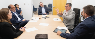 A group of professionals engages in discussion around a table, with one person animatedly speaking while others listen intently.