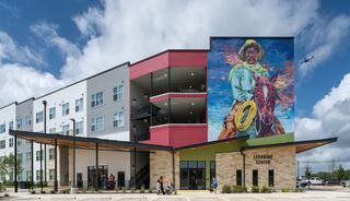 A modern affordable housing residential complex with outdoor recreational areas, featuring courts, pathways, and green spaces, creating a vibrant community atmosphere.