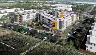 A modern multi-story affordable housing complex featuring colorful balconies, landscaped surroundings, and ample parking.