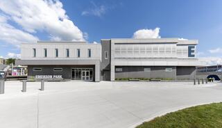 Modern building with a sleek design, featuring large windows and clear signage for Emerson Park, set against a blue sky with clouds.
