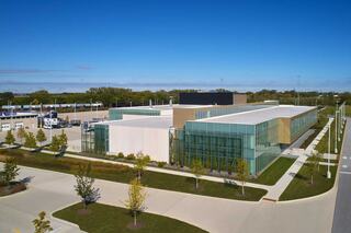 Exterior of City Colleges of Chicago-Olive-Harvey College's Transportation, Distribution and Logistics learning facility; featuring walls of glass and ample natural light with a large driving lot in the back.