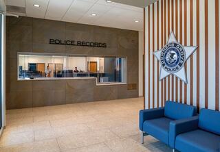 A modern police records office features a reception area, a large wall sign, and a blue seating area, creating a welcoming environment.