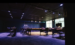Virtual reality learning lab featuring two rows of long tables and chairs at each virtual reality workstation, overhead theater lights and Dreamscape Learn logo on the back wall