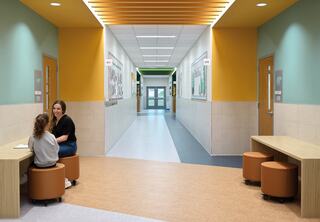 A bright hallway with colorful walls features a seating area where two people converse, highlighting a welcoming, modern environment.