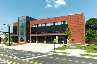 A modern fire department building features a mix of brick and glass, with clear signage and landscaped areas in a well-maintained urban setting.