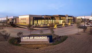A modern building features a welcoming design, with landscaping and signage indicating it houses the City of Roanoke's Police Department.