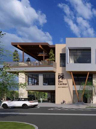 A modern recreational center features a stylish facade, outdoor seating, and a clean landscape, blending functionality with contemporary design.