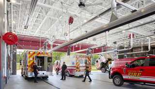 A bustling fire station with emergency vehicles, firefighters, and a bright, spacious interior designed for quick response and teamwork.