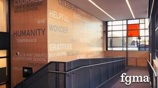 A modern hallway features a wooden wall adorned with inspiring words and values, creating an uplifting atmosphere for visitors.