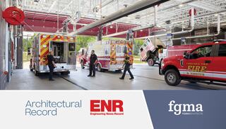 Emergency vehicles are stationed in a modern fire station, with firefighters and equipment visible in a well-lit interior space.