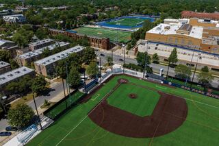 An aerial view showcases a vibrant sports complex featuring a baseball field and soccer fields, surrounded by lush greenery and buildings.